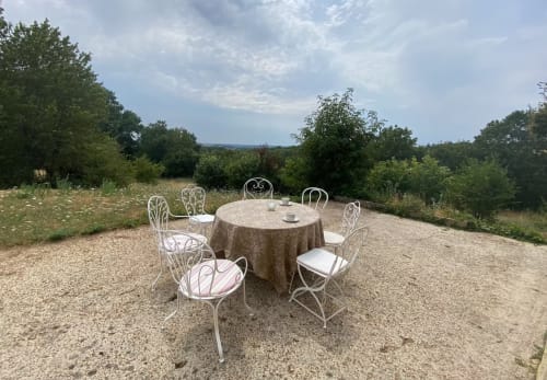 Comedor al aire libre con sillas metálicas blancas alrededor de una mesa redonda con vistas al paisaje rural cerca de Oliva, España