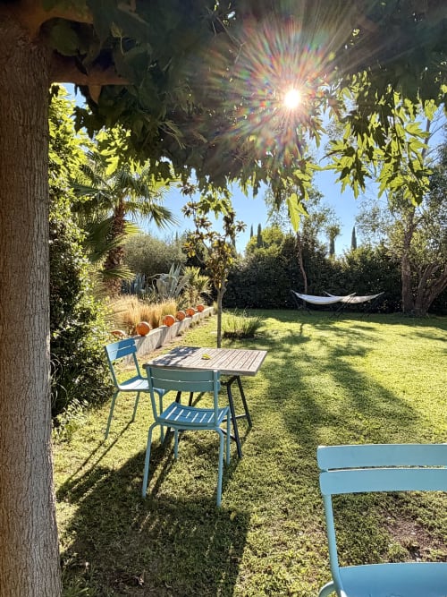 Jardin ensoleillé de la maison d'hôtes Maison Jalon à Aix-en-Provence avec chaises bleues, table et hamac