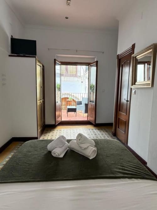 Entrada moderna de habitación con toallas enrolladas, puertas de madera y vista al balcón en Hotelito Oliva Pensión, Oliva