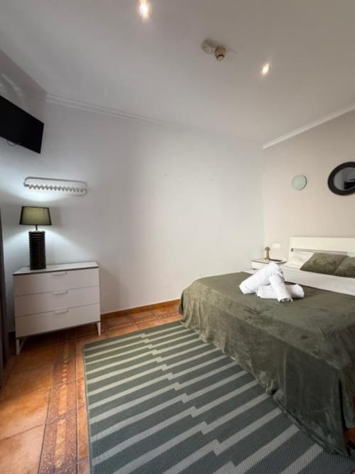 Dormitorio doble moderno en Hotelito Oliva Pensión en Oliva con cama, lámpara de mesita, alfombra a rayas y vistas a la ciudad