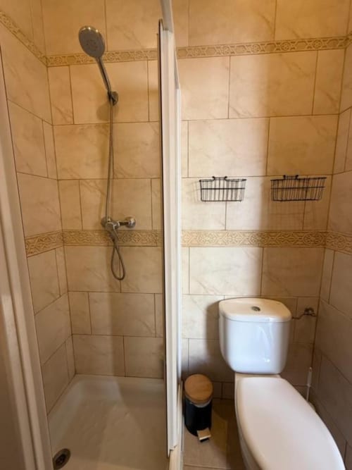 Baño de Hotelito Oliva Pensión en Oliva con ducha alicatada, inodoro y cestas de almacenamiento
