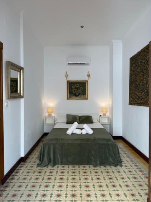 Elegante habitación doble en Hotelito Oliva con detalles verdes, lámparas gemelas y arte decorativo en pared