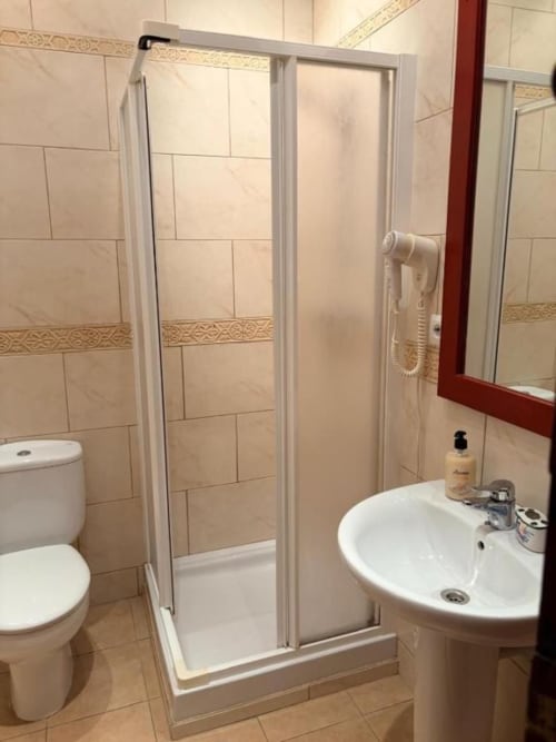 Baño moderno con ducha, lavamanos blanco e inodoro en Hotelito Oliva Pensión, Oliva, España