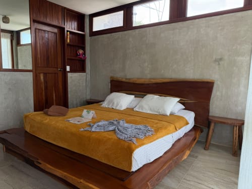 Dormitorio de madera con colcha amarilla en el hostel Cayuco Maya de Bacalar, México, con vistas al lago y decoración rústica