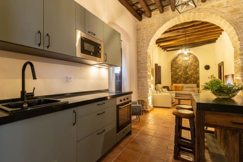 Cocina moderna con arco de piedra que conecta hacia la sala de estar en los Apartamentos G&H, Jerez de la Frontera
