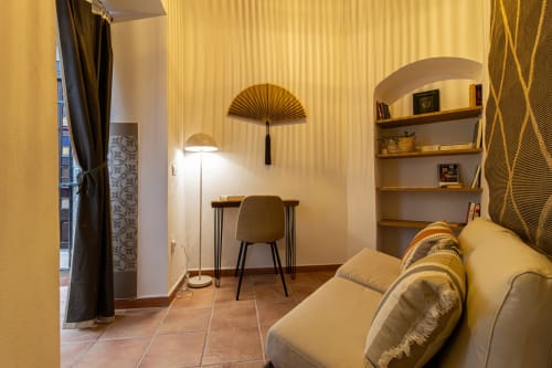 Acogedora sala de estar en los Apartamentos G&H de Jerez de la Frontera con sofá crema, escritorio y estantería mural