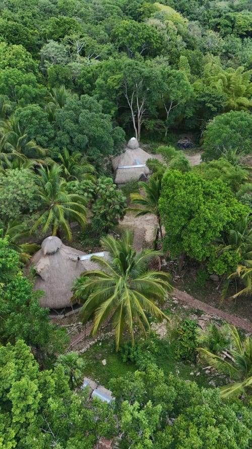 Vista aérea de bungalós con techos de paja rodeados de exuberante selva en el hostel Cayuco Maya, Bacalar, México