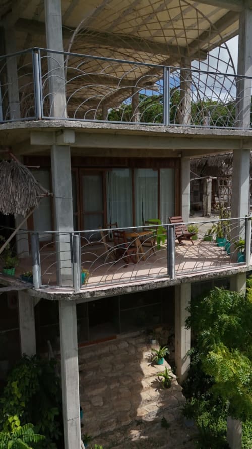 Terraza multinivel en el hostel Cayuco Maya de Bacalar con barandales modernos, vistas al lago y zona de descanso sombreada