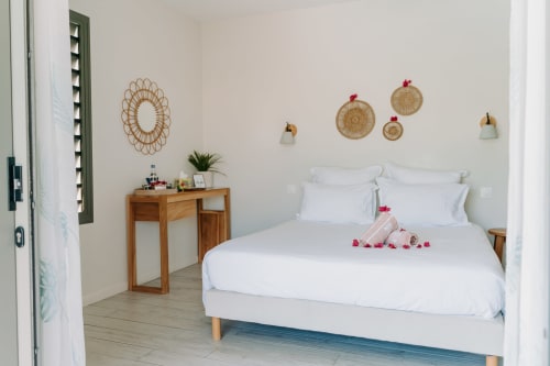 Chambre contemporaine à l'Habitation l'SEO à Sainte-Anne avec literie blanche, bureau en bois et décoration murale inspirée du littoral
