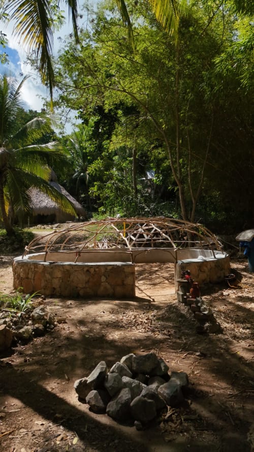 Estructura rústica de palapa en construcción en el hostal Cayuco Maya de Bacalar, México, rodeada de vegetación tropical