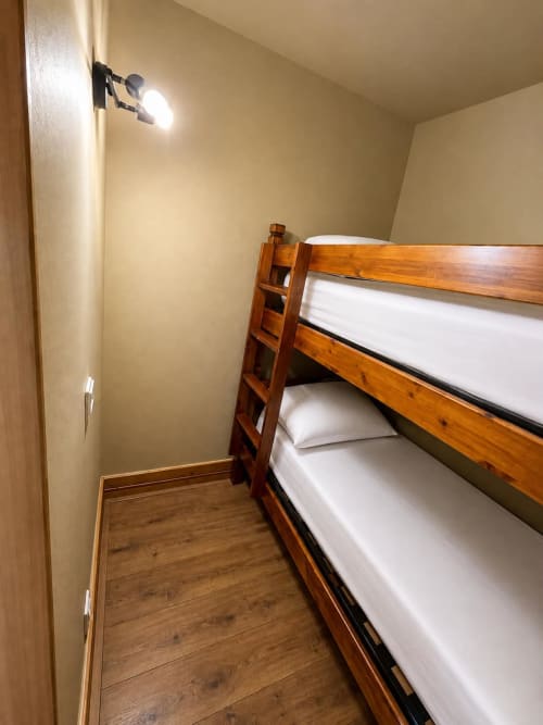 Cozy bunk bed room at Le Chalet des Cimes in Belle Plagne with wooden furnishings and white bedding