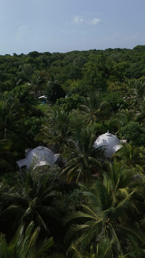 Domos geodésicos blancos entre exuberantes jardines de selva en el hostel Cayuco Maya, Bacalar, México