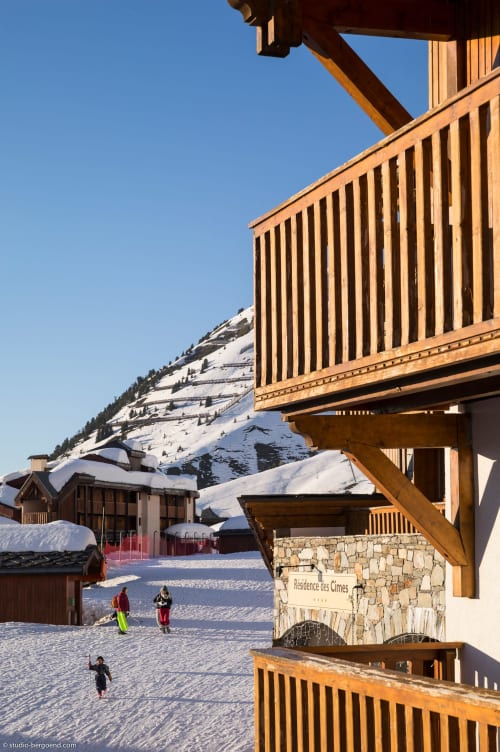Le Chalet des Cimes en station alpine de Belle Plagne : sommets enneigés, balcons en bois, clients en hiver