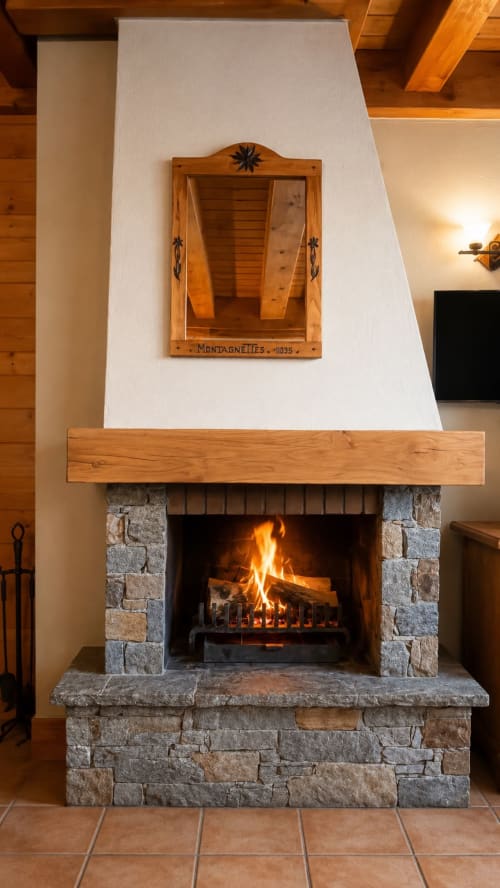 Cheminée avec feu allumé, manteau en bois, entourage en pierre et miroir en bois au-dessus au Chalet des Cimes, Belle Plagne