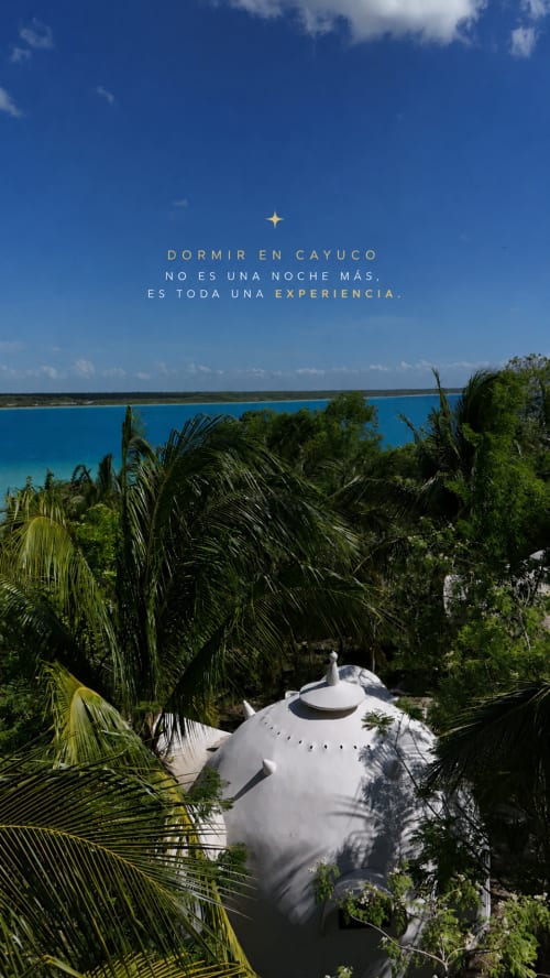 Domo geodésico blanco rodeado de palmeras con vistas a la laguna turquesa de Bacalar en el glamping Cayuco Maya