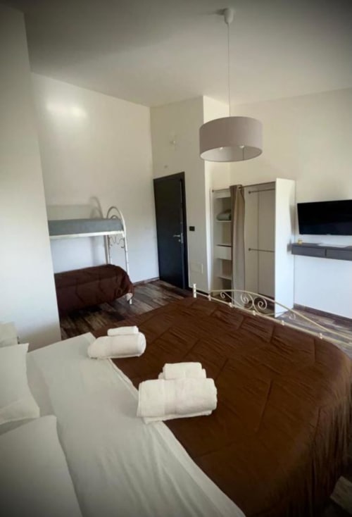 Chambre spacieuse au B&B Helios à Nardò avec lits doubles, serviettes blanches, lampe suspendue et équipements modernes