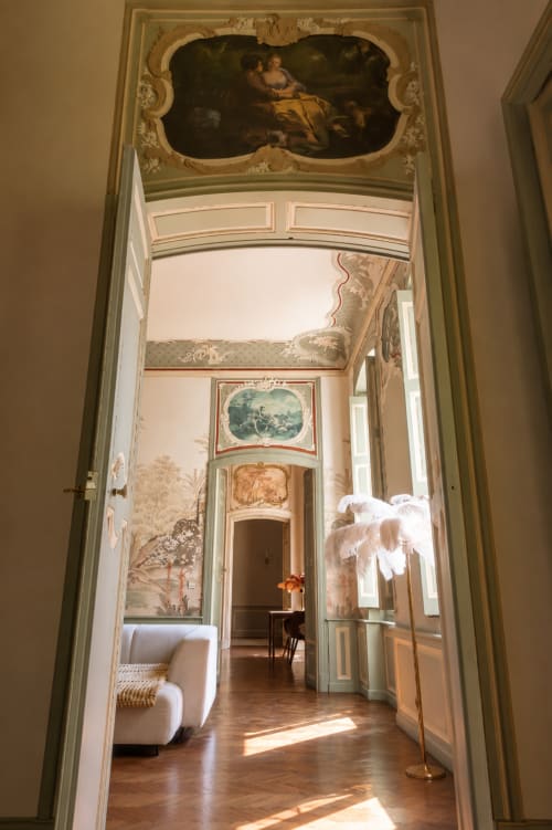 Elegant hallway in Les Suites de Montigny, Aix-en-Provence, with classical frescoes, ornate ceiling, and glimpse of furnished