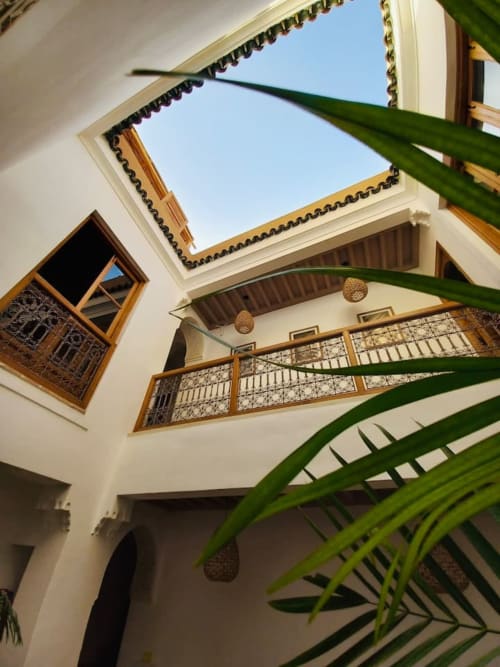 Riad Casa Angelo courtyard in Marrakech with skylight, wooden railings, and green plant leaves