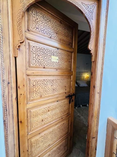 Portail voûté en bois richement sculpté du Riad Casa Angelo à Marrakech orné de motifs géométriques islamiques