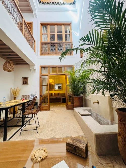 Cour du Riad Casa Angelo à Marrakech avec palmiers, portes en bois, salle à manger et architecture traditionnelle
