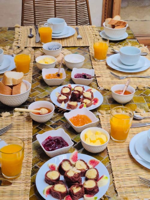 Table du petit-déjeuner du Riad Casa Angelo à Marrakech avec viennoiseries, fruits frais, jus et cuisine marocaine traditionnelle