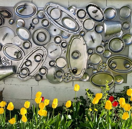 Plaques décoratives en métal sur mur en béton au-dessus de tulipes jaunes aux Logis du canal, Betton