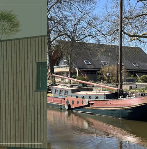 Péniche traditionnelle amarrée aux Logis du Canal à Betton, France, avec arbres printaniers et immeubles résidentiels en arrière-plan