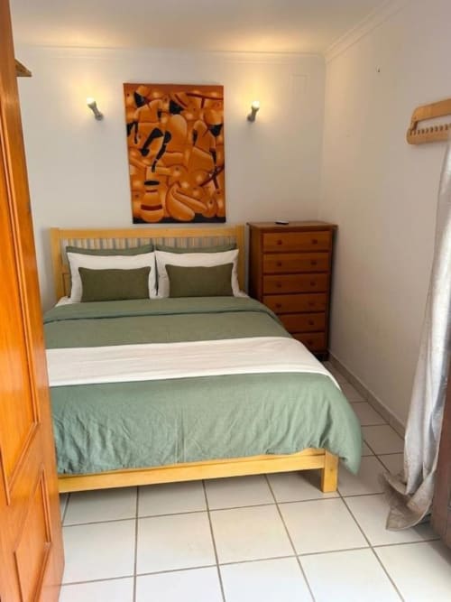 Acogedora habitación doble en Hotelito Oliva con ropa de cama verde, muebles de madera y comodidades modernas cerca de la playa de Oliva