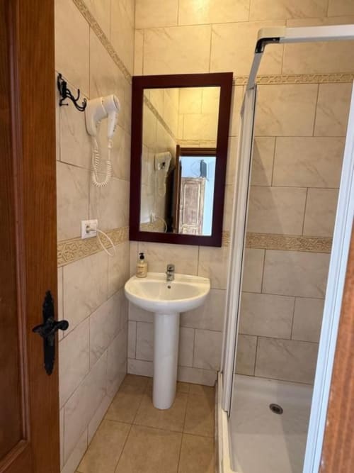 Baño moderno del Hotelito Oliva Pensión con lavamanos pedestal, espejo, cabina de ducha y paredes alicatadas en Oliva