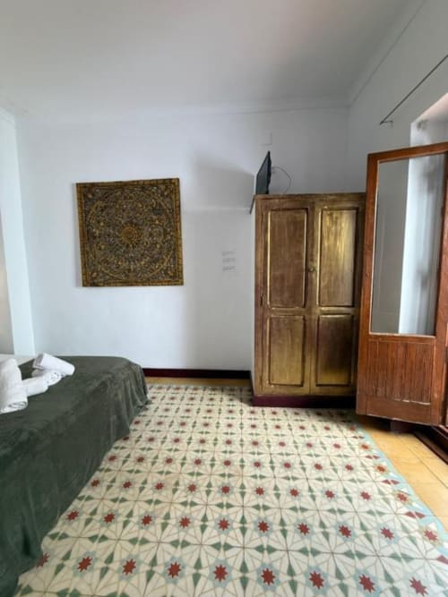 Habitación doble en Hotelito Oliva Pensión de Oliva con cama, armario de madera, piso de azulejos decorativos y arte mural