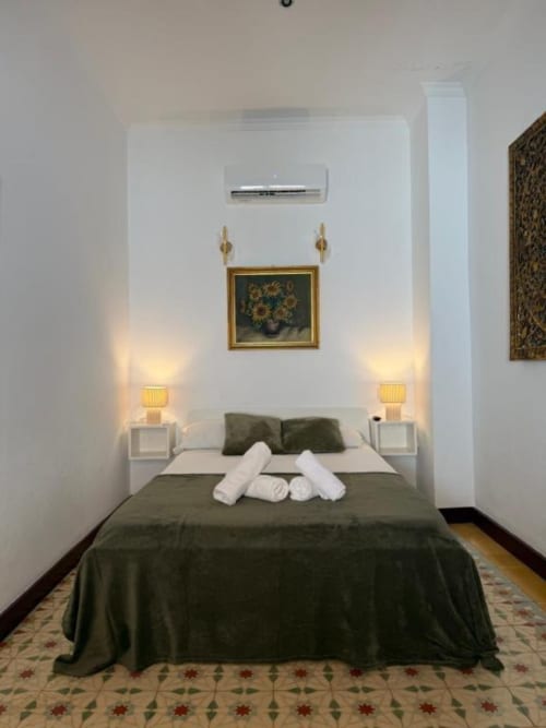 Acogedora habitación doble en Hotelito Oliva Pensión, Oliva, España, con ropa de cama verde oliva, lámparas de noche y aire acondicionado