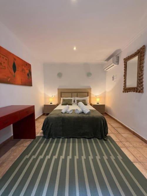 Habitación doble en Hotelito Oliva Pensión en Oliva con cama de madera, ropa blanca, toallas enrolladas, muebles rojos y tapizado a rayas