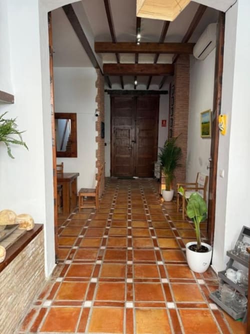 Entrada del pasillo en Hotelito Oliva Pensión en Oliva, España, con baldosas de barro cocido, vigas de madera y puerta doble