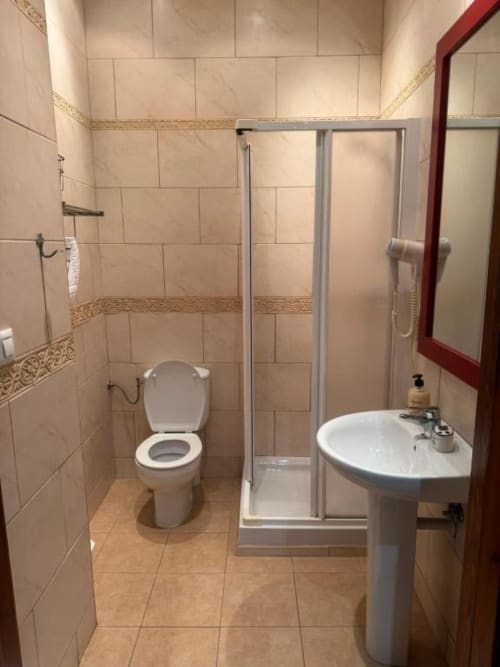 Baño moderno y limpio en Hotelito Oliva Pensión en Oliva con ducha, inodoro y lavamanos pedestal