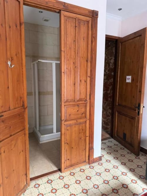 Entrada del baño del hotel con puertas de madera y cabina de ducha en Hotelito Oliva Pensión, Oliva España