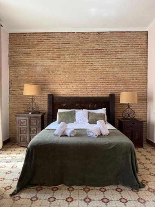Habitación doble en Hotelito Oliva Pensión, Oliva, España, con cama de madera oscura, ropa de cama verde y pared de ladrillo visto
