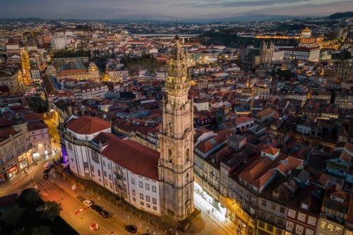 Vista aérea do centro da cidade de Maia, Portugal ao entardecer, com torre iluminada e edifícios de telhado vermelho