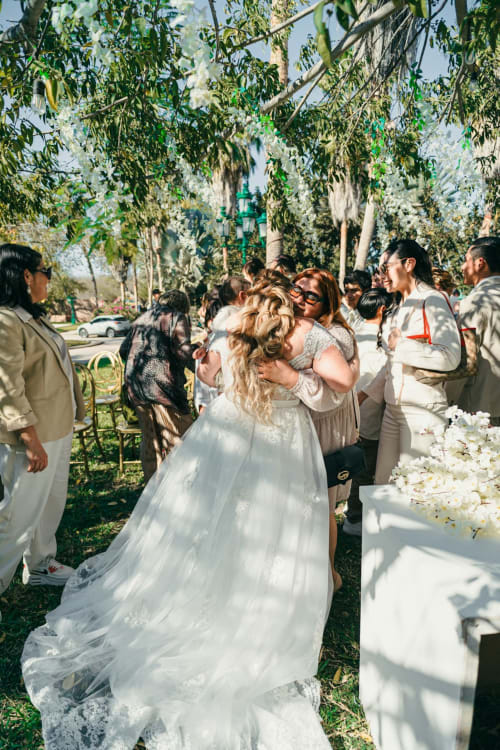 Mariée embrassant un invité lors de la cérémonie de mariage en plein air sous des arbres en fleurs aux Logis du Canal, Betton