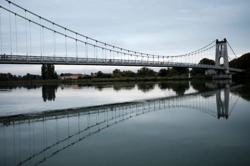 Pont suspendu enjambant une rivière calme reflétant le ciel, près de l'auberge Yasi à Lyon, France