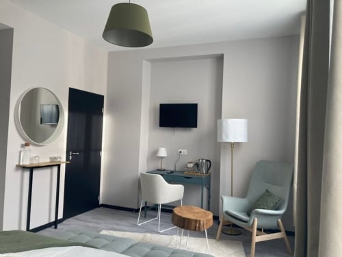Chambre d'hôtel moderne au relais de Touraine à Abilly avec bureau, fauteuil vert et téléviseur écran plat