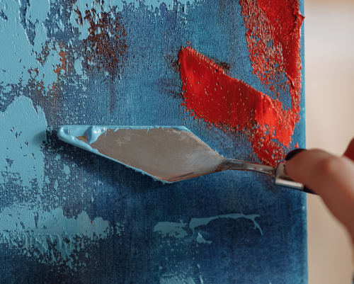 Grattoir à peinture enlevant la vieille peinture rouge du mur bleu usé par le temps du château Haute Roche à Oudon, France