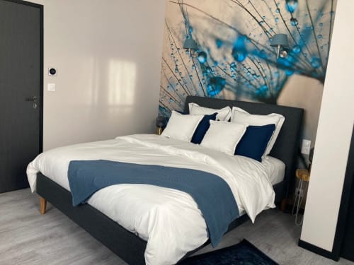 Chambre moderne de l'hôtel Le relais de Touraine à Abilly avec lit sombre, draps blancs, accents bleus et décoration murale de pissenlit