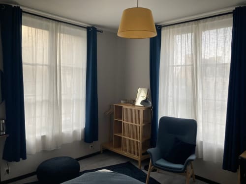 Chambre d'hôtel moderne au Relais de Touraine à Abilly avec rideaux bleus, mobilier en bois et luminaires suspendus