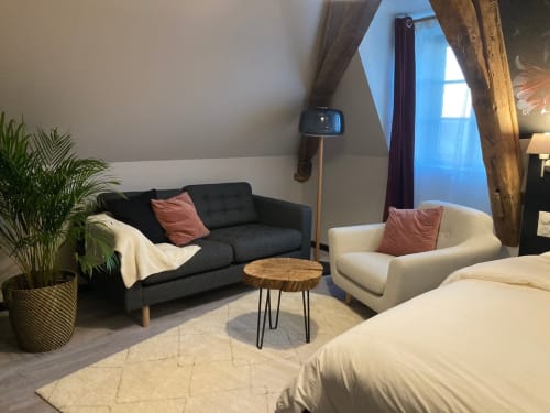 Chambre moderne au Relais de Touraine à Abilly avec canapé noir, fauteuil crème et poutres en bois