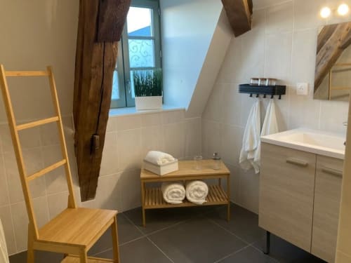 Salle de bain moderne au Relais de Touraine avec vasque en bois, carrelage et lumière naturelle de la fenêtre