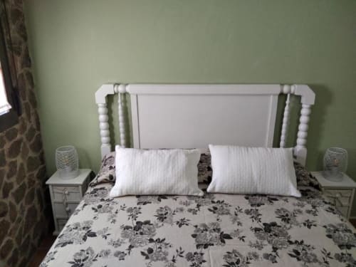 Habitación en el apartamento Casa Lahuerta con cama con dosel blanca, ropa de cama floral, almohadas blancas y paredes verde salvia en Bronchales
