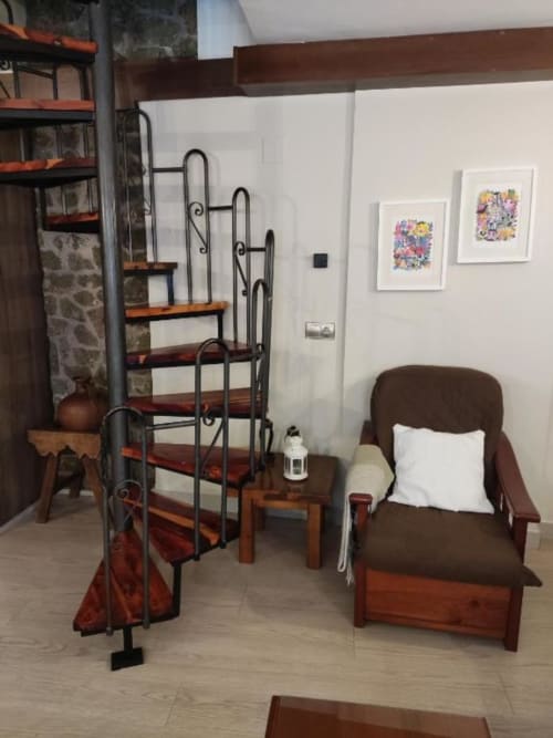 Interior rústico de apartamento con escalera de caracol de madera, sillón marrón, arte floral decorativo y estilo tradicional