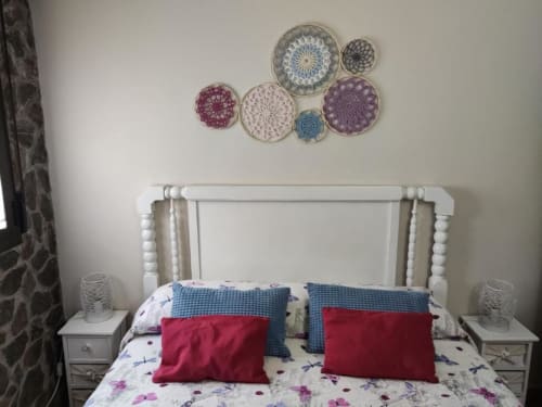 Dormitorio acogedor en apartamento Casa Lahuerta con cama de madera blanca, platos decorativos coloridos en pared, almohadas rojas y florales