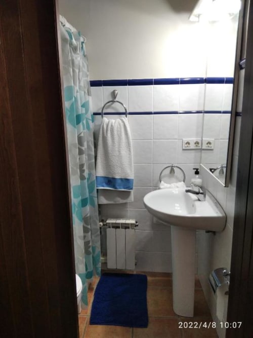 Baño limpio en apartamento Casa Lahuerta con lavabo de pedestal blanco, paredes alicatadas, toallero y detalles azules en Casas
