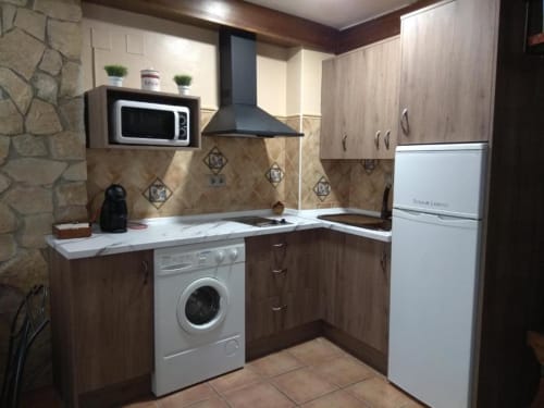 Cocina moderna en apartamento Casa Lahuerta con muebles marrón, electrodomésticos blancos, encimeras de mármol y azulejos decorativos